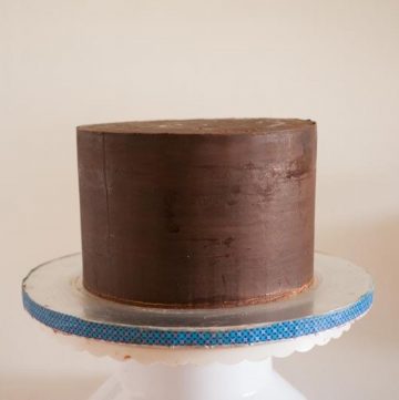 A cake with sharp edges covered in ganache.