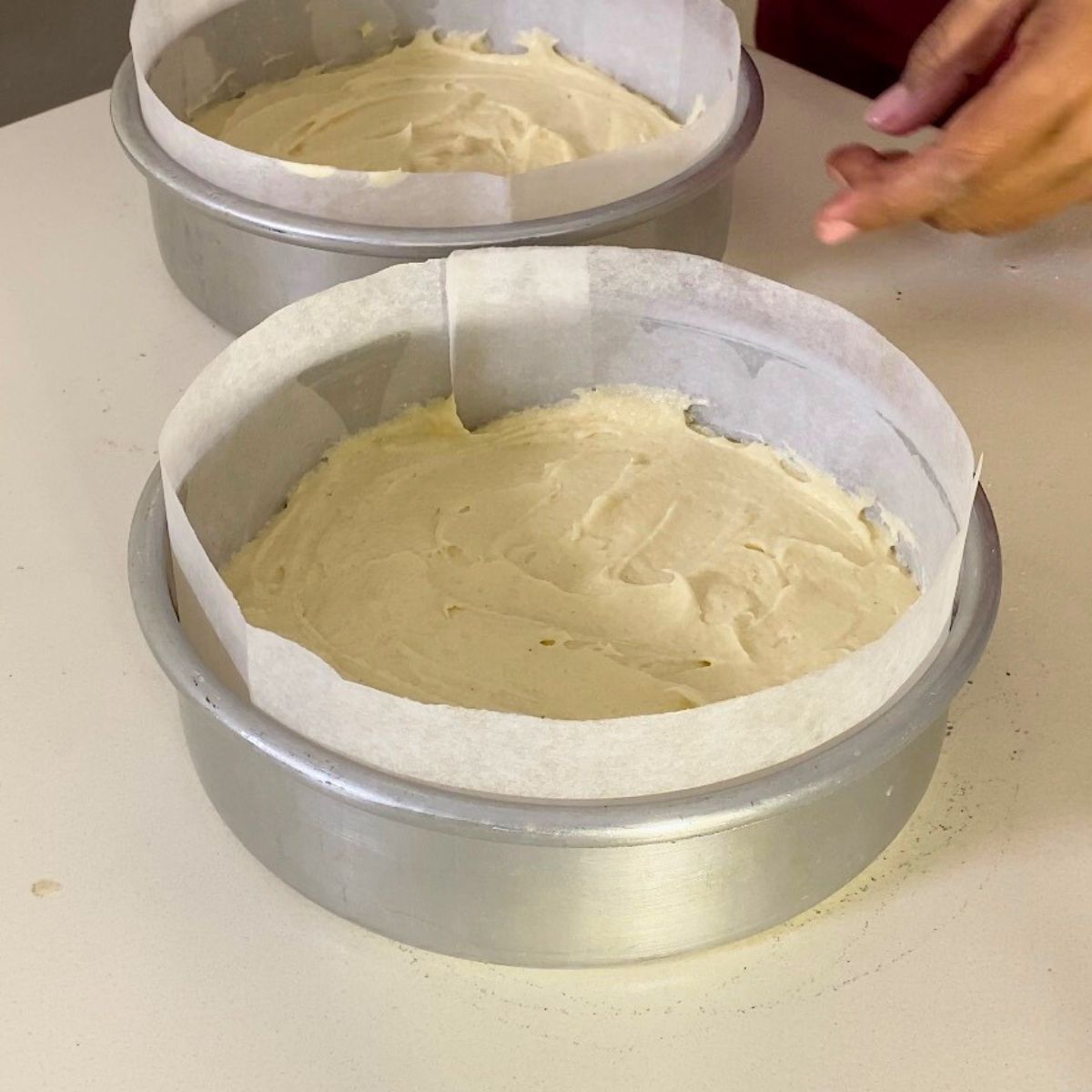Two baking pans with vanilla cake.
