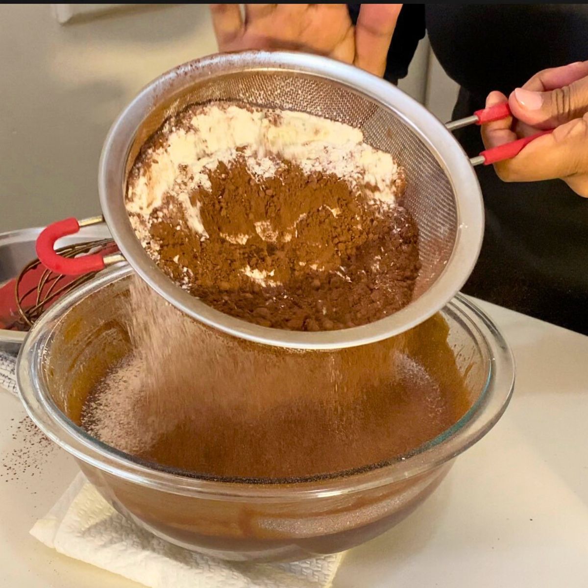 Progress pictures adding flour and cocoa powder to chocolate batter.
