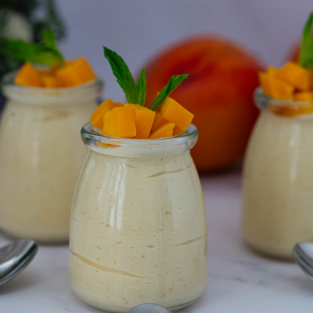 Jars with mango mousse and fresh mango slices.