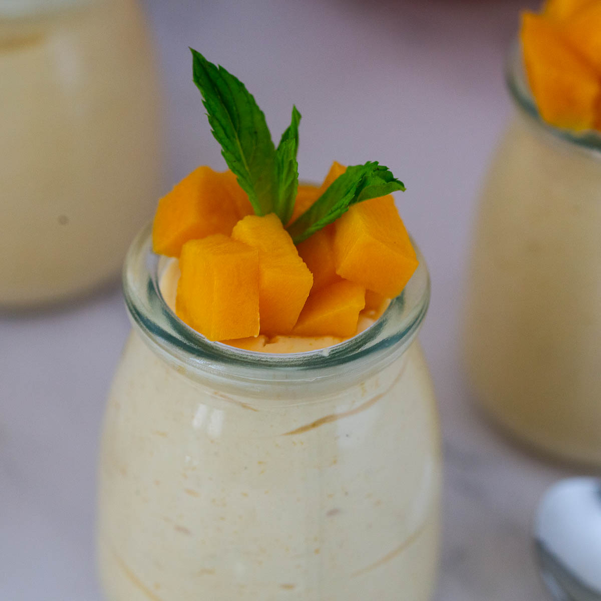 A jar with mango mousse and fresh mango cubes.