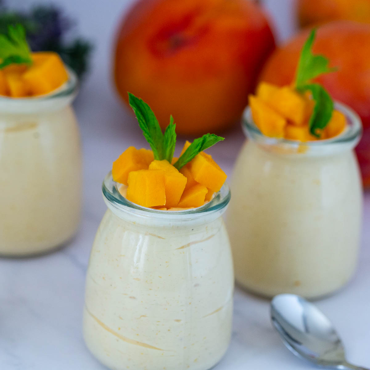 Jars with fresh mango mousse and fresh mango.