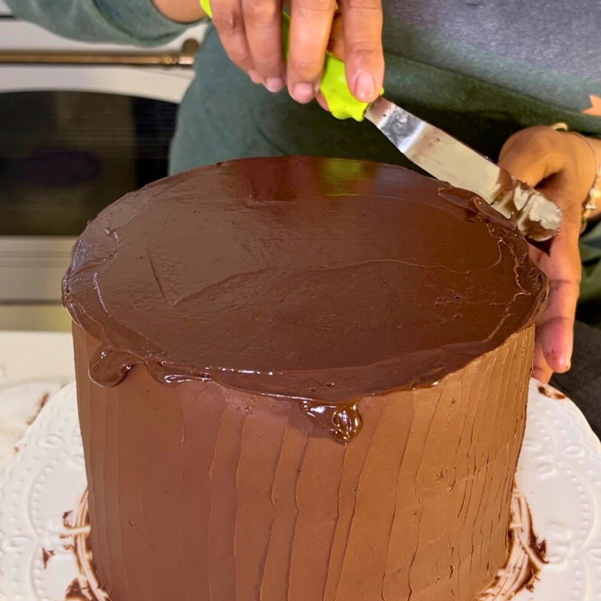 Spreading melted chocolate on the devils food cake.