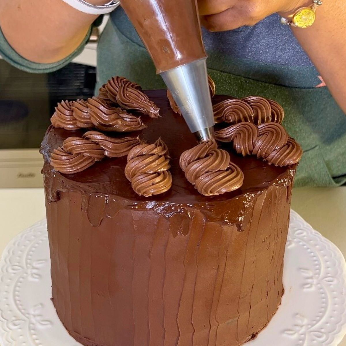 Piping chocolate ganache on the cake.