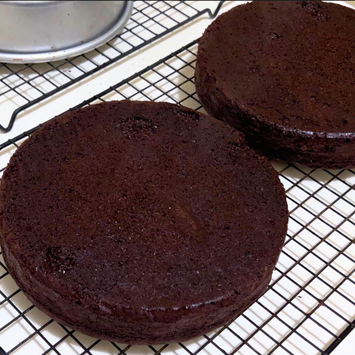 Devils food cake layers fresh baked on a rack.