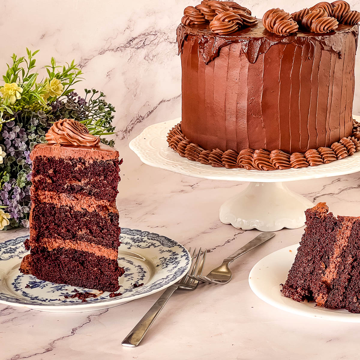 A slice of dark Devil’s Food chocolate cake with a soft crumb and glossy chocolate ganache frosting.