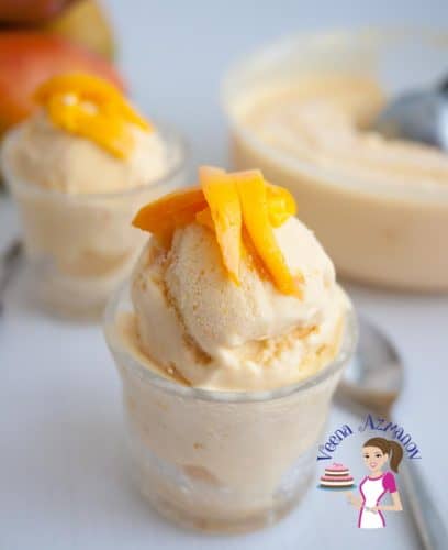 A scoop of mango flavored no-churn ice cream in a bowl topped with fresh mangoes