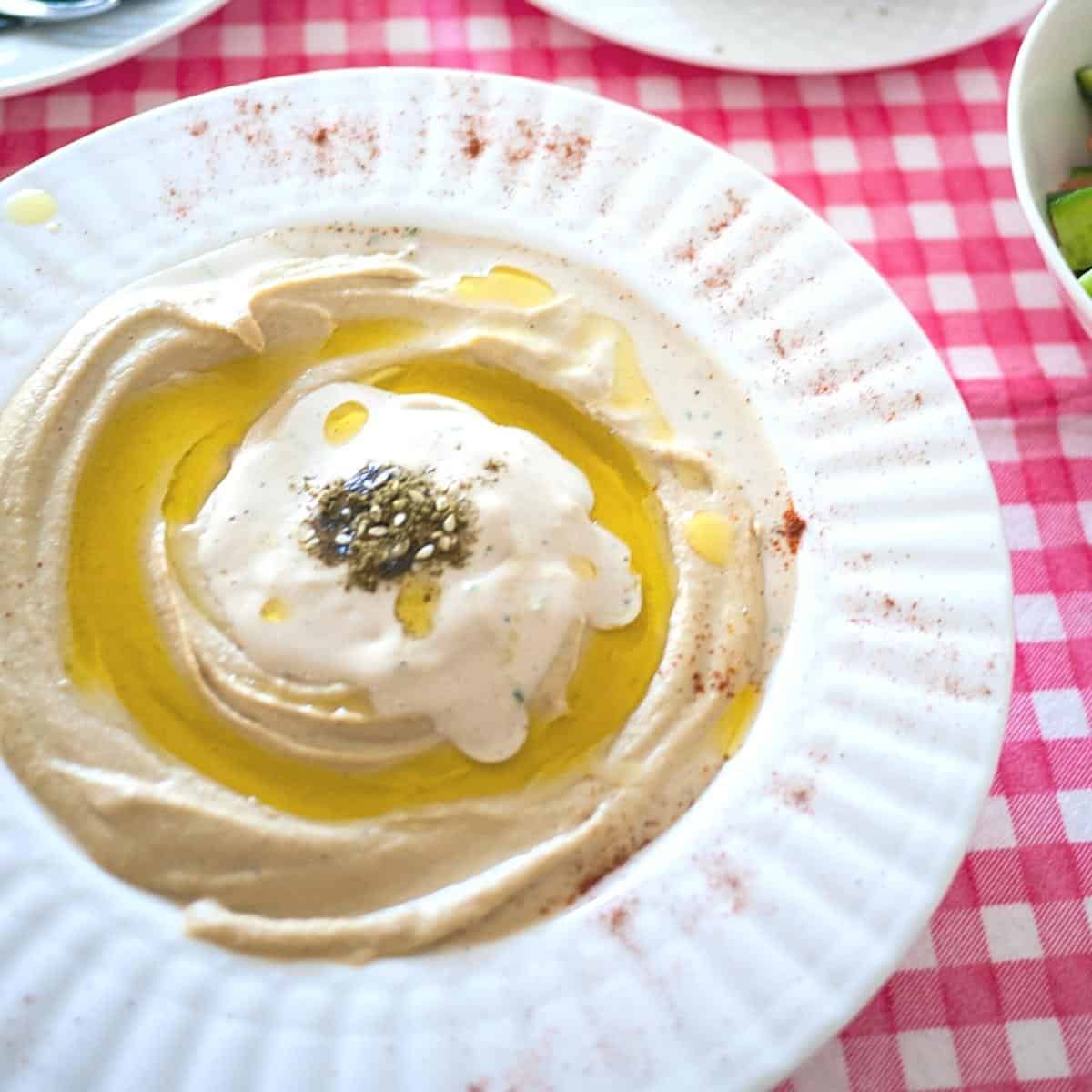A plate with hummus tahini and oil.
