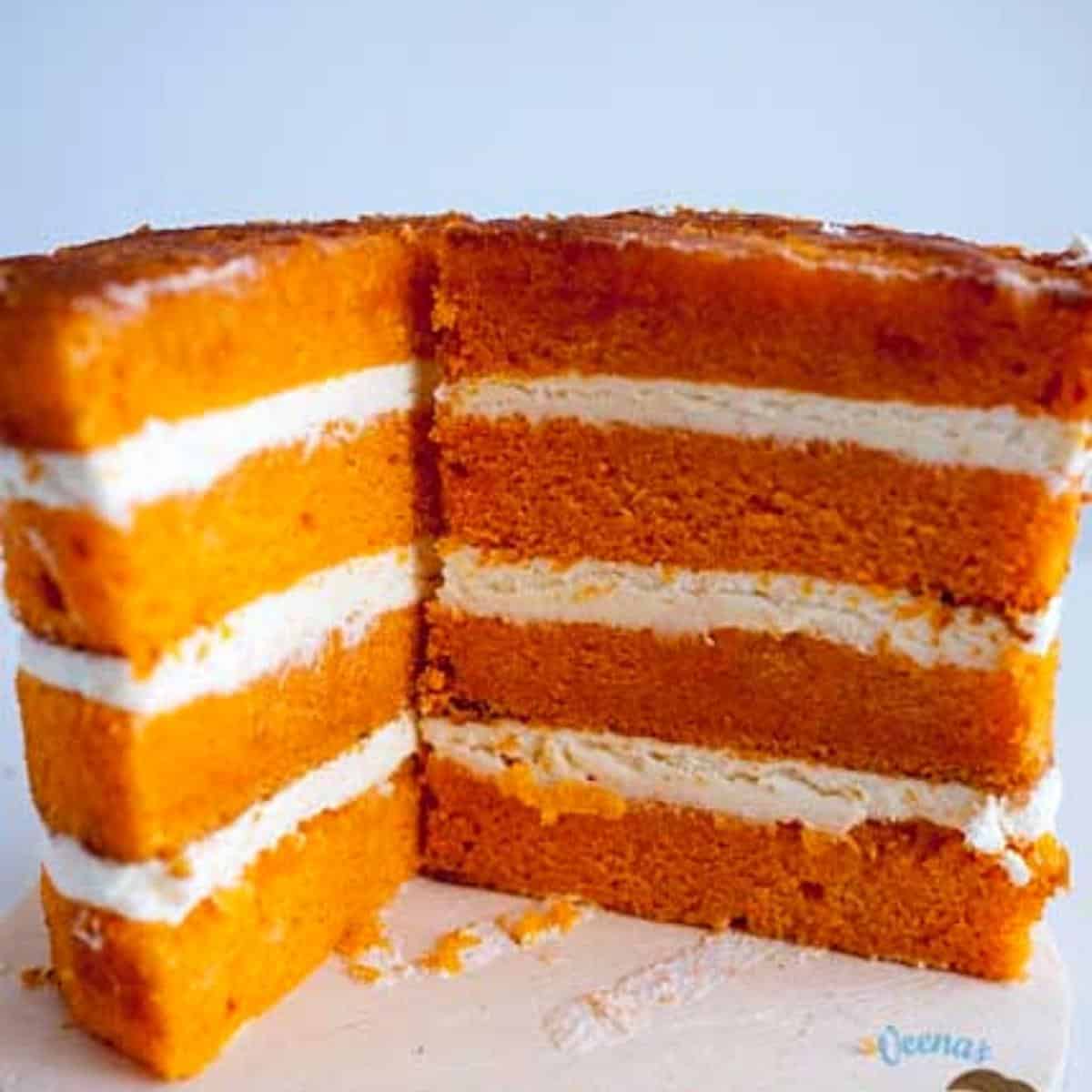 Sliced layers of orange cake with white frosting.