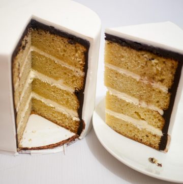 A cut vanilla cake on a cake board.