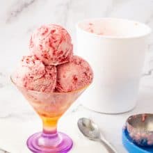 An ice cream scoop with raspberry ice cream.