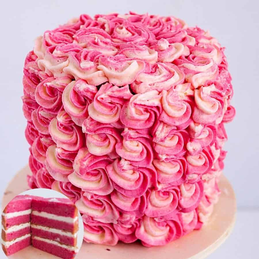 A frosted strawberry layer cake on a cake board.