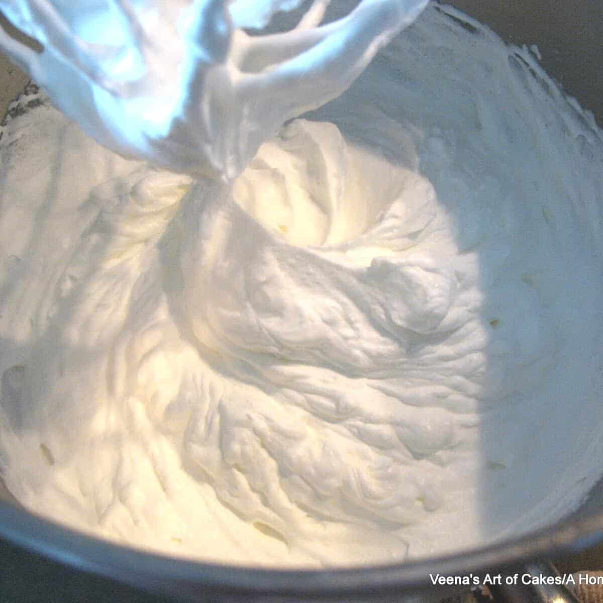Bowl of a stand mixer with whipped cream.