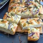 Sliced focaccia bread on a wooden board.