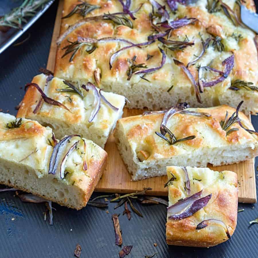 Sliced focaccia bread on a wooden board.