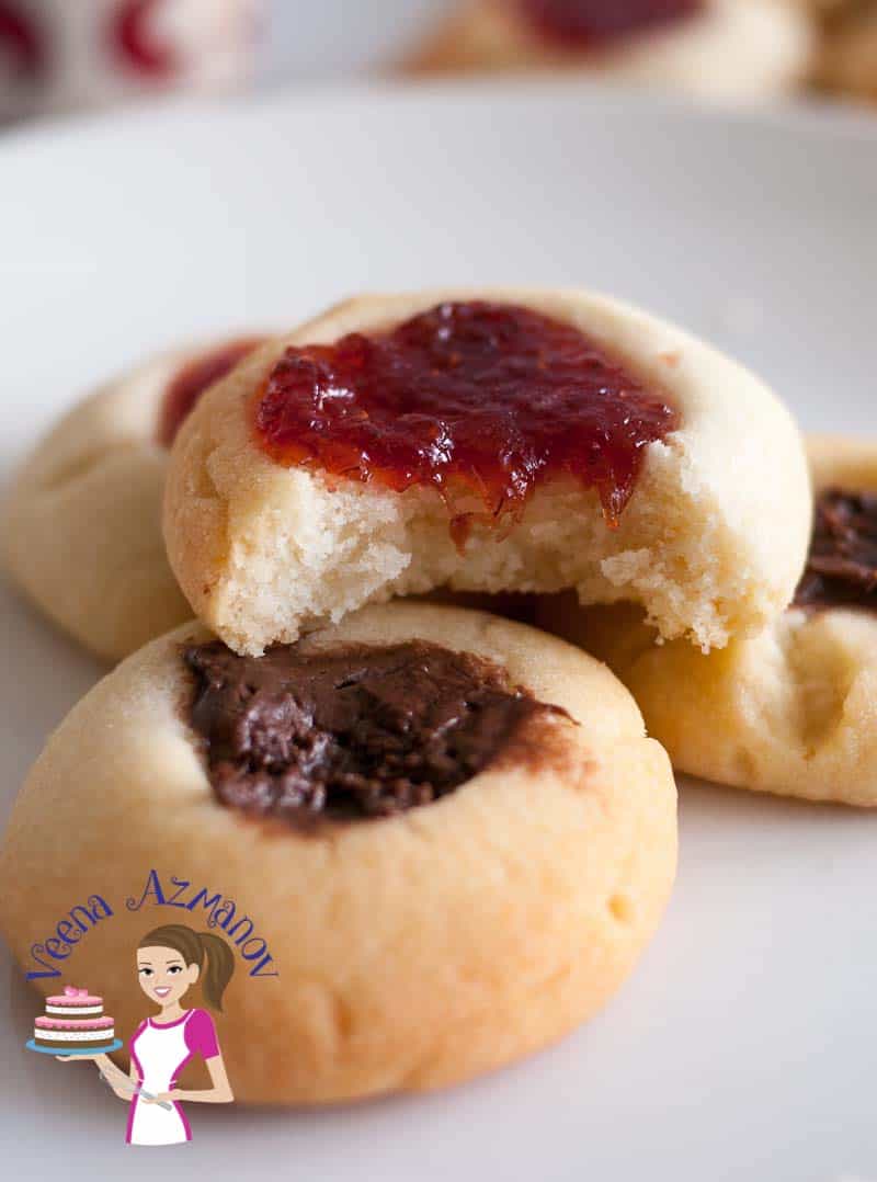 A close up of thumbprint cookies with jams and chocolates.