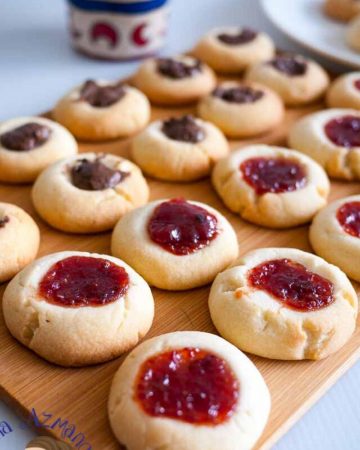A tray of thumbprint cookies with jams and chocolates.