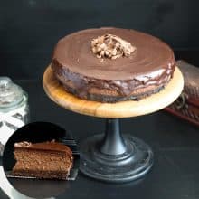 Cake stand with baked cheesecake with chocolate glaze.