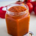 A glass jar filled with tomato sauce.