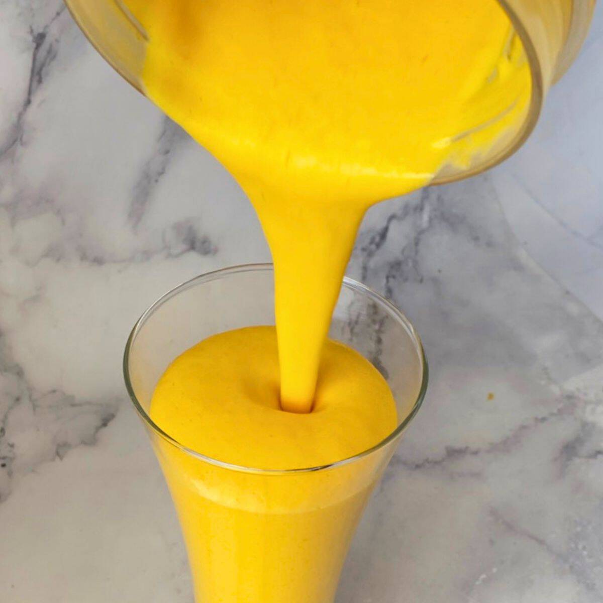 Pouring Mango lassi into the glass.