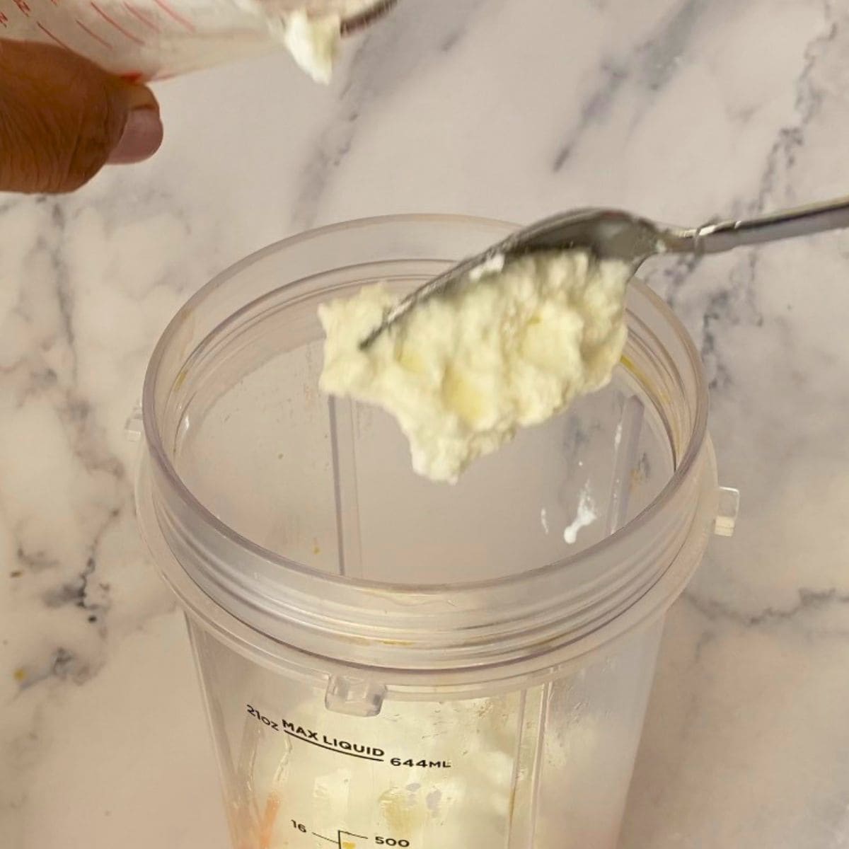 Adding Greek yogurt to the blender.