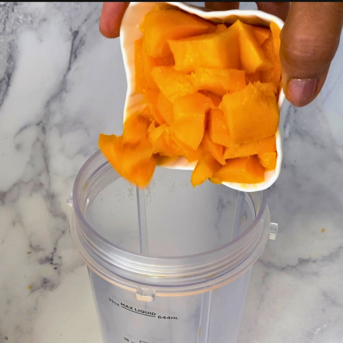 Adding mango to the blender.
