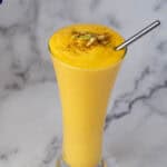 A glass with mango yogurt lassi.