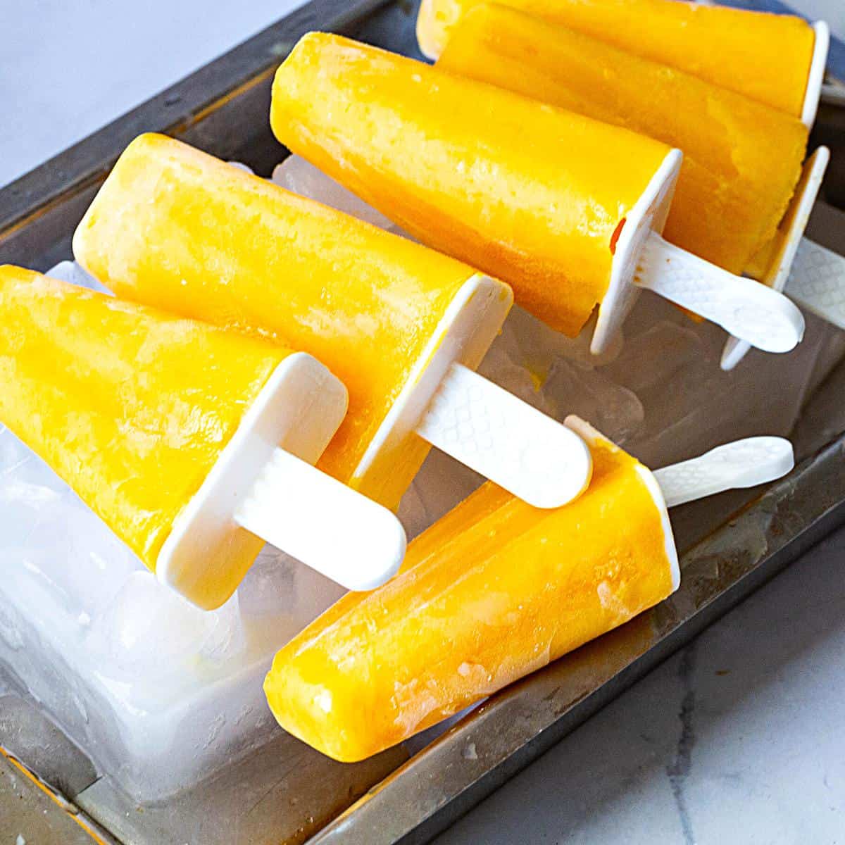 Mango popsicles on a tray of ice.