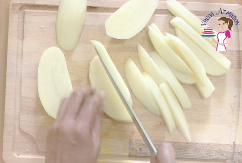 A person cutting potatoes into wedges.