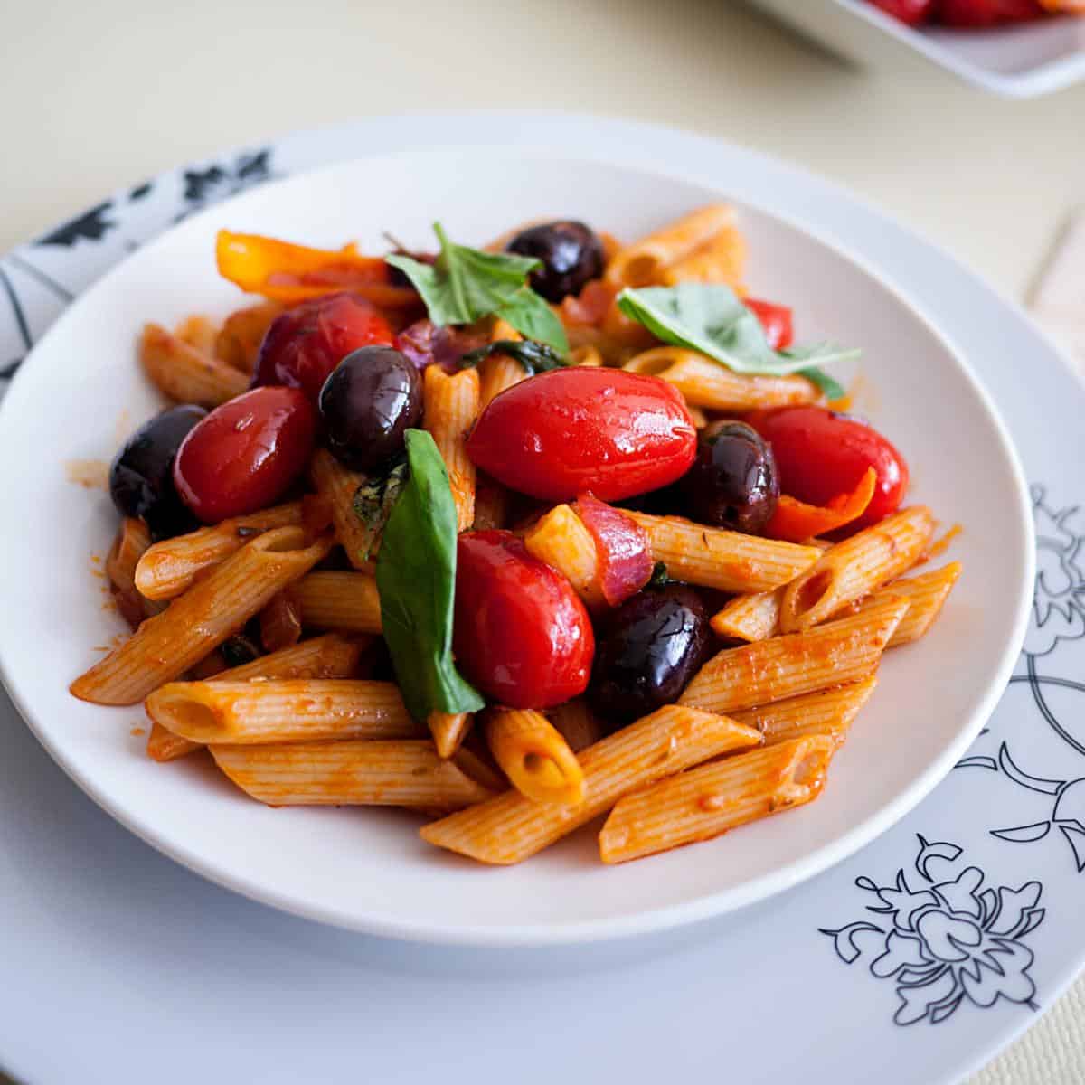 A plate with pasta and cherry tomatoes.