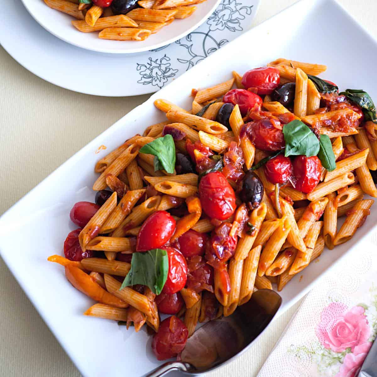 A tray with pasta tomatoes and olives.
