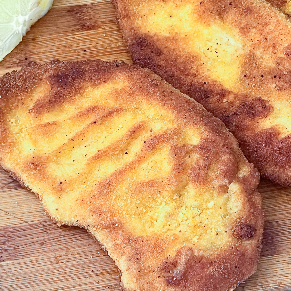 Chicken breast breaded on a wooden board.