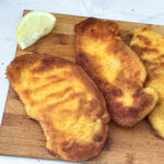 Chicken breaded breast on a wooden board.