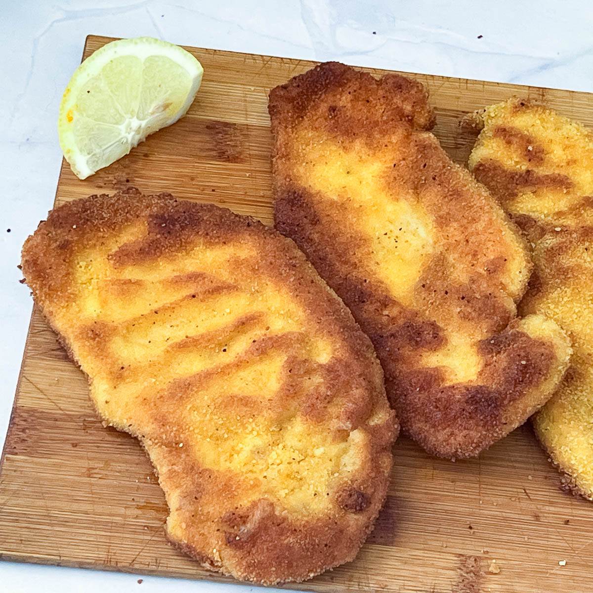 Chicken breaded breast on a wooden board.