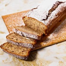 A sliced banana loaf cake on a wooden board.