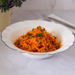 A white bowl with fresh carrot salad.