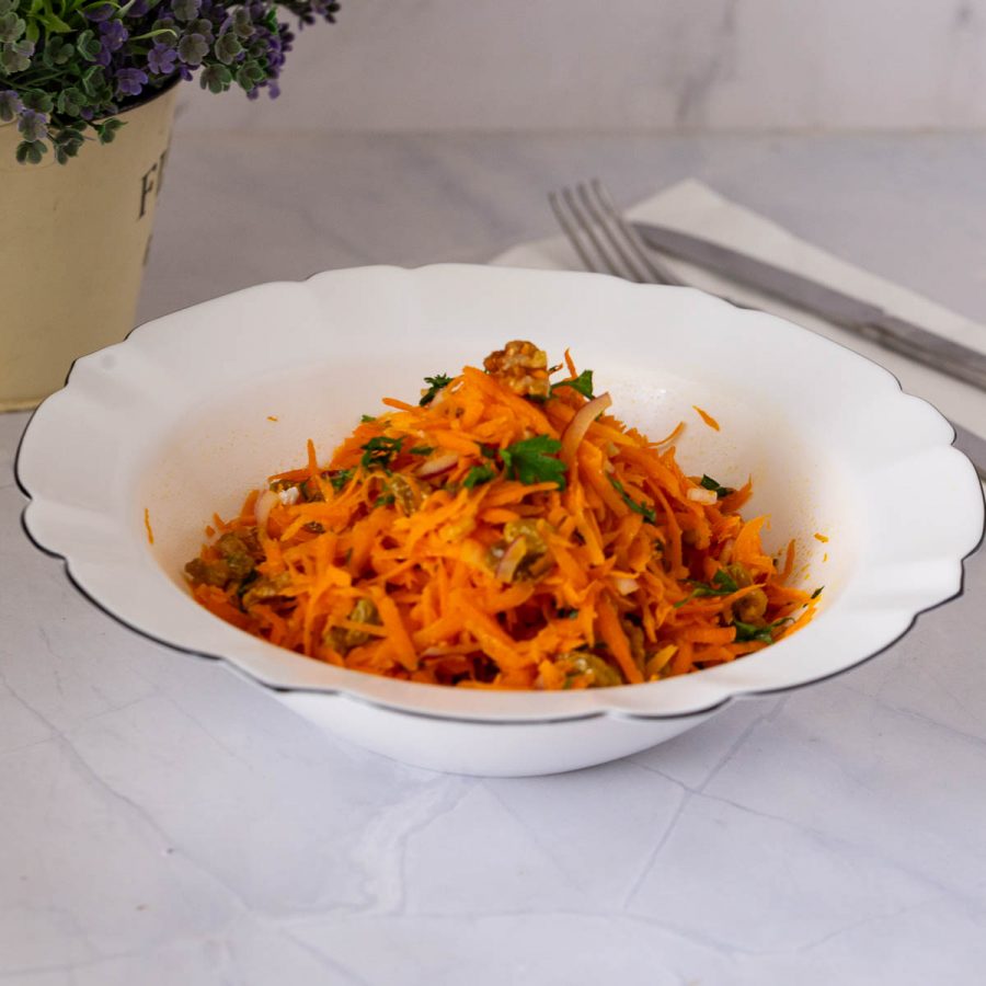A white bowl with fresh carrot salad.