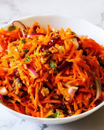 Bowl with carrot salad made of cranberries, raisins, walnuts.