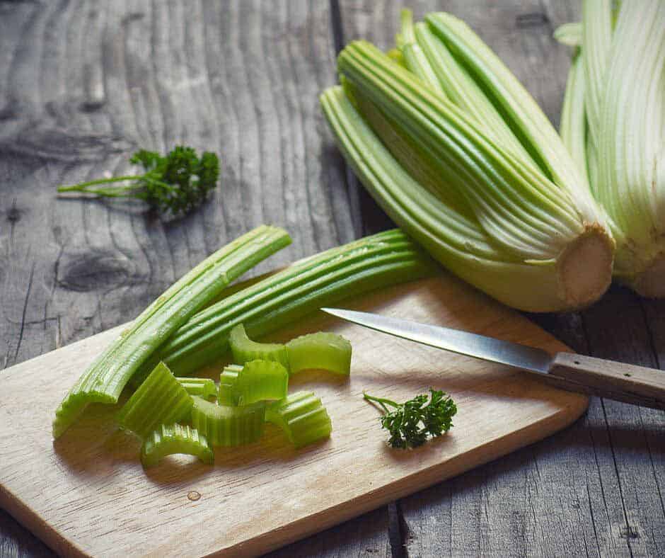 Cutting celery on a cutting board.