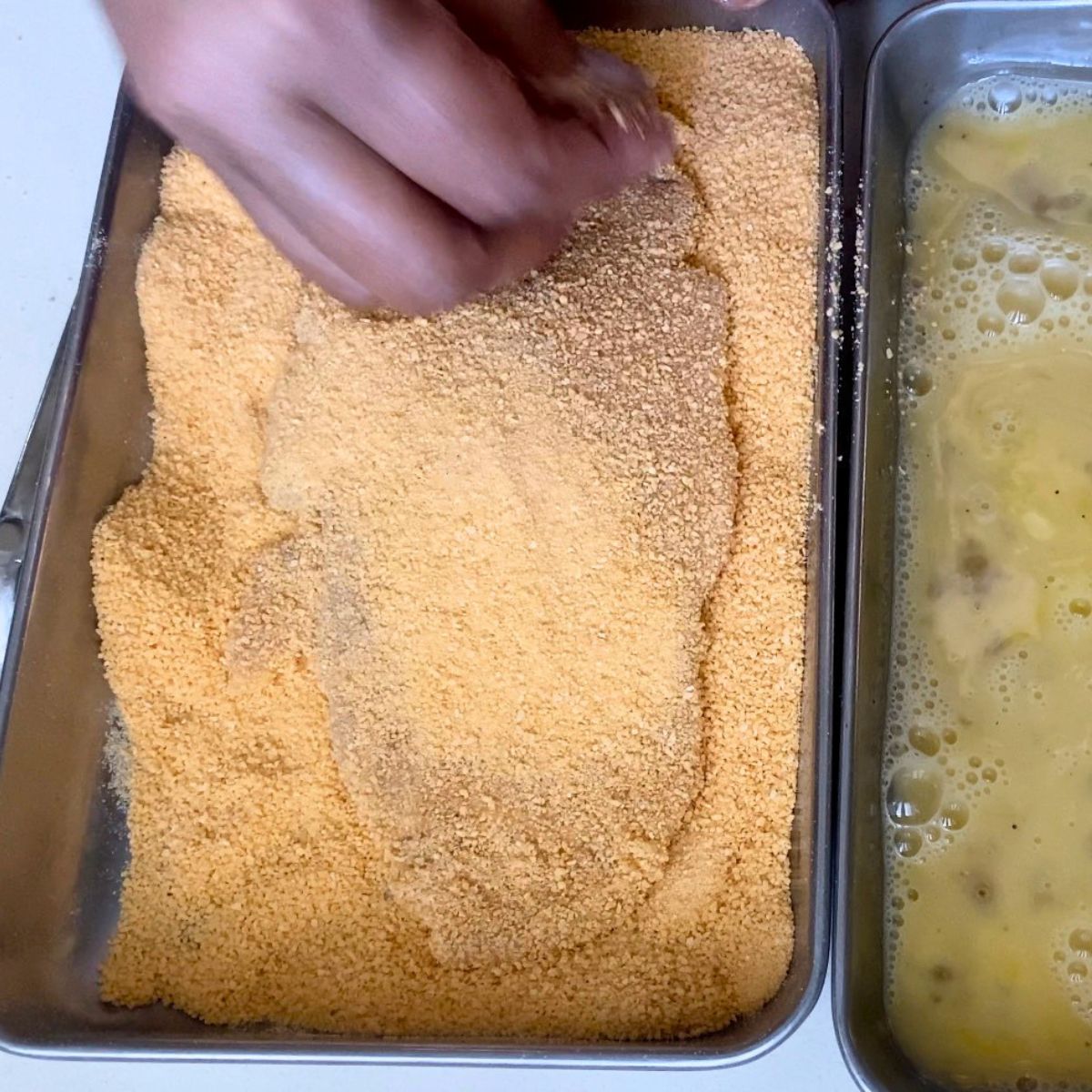 Coating the chicken breast cutlets in breadcrumbs.