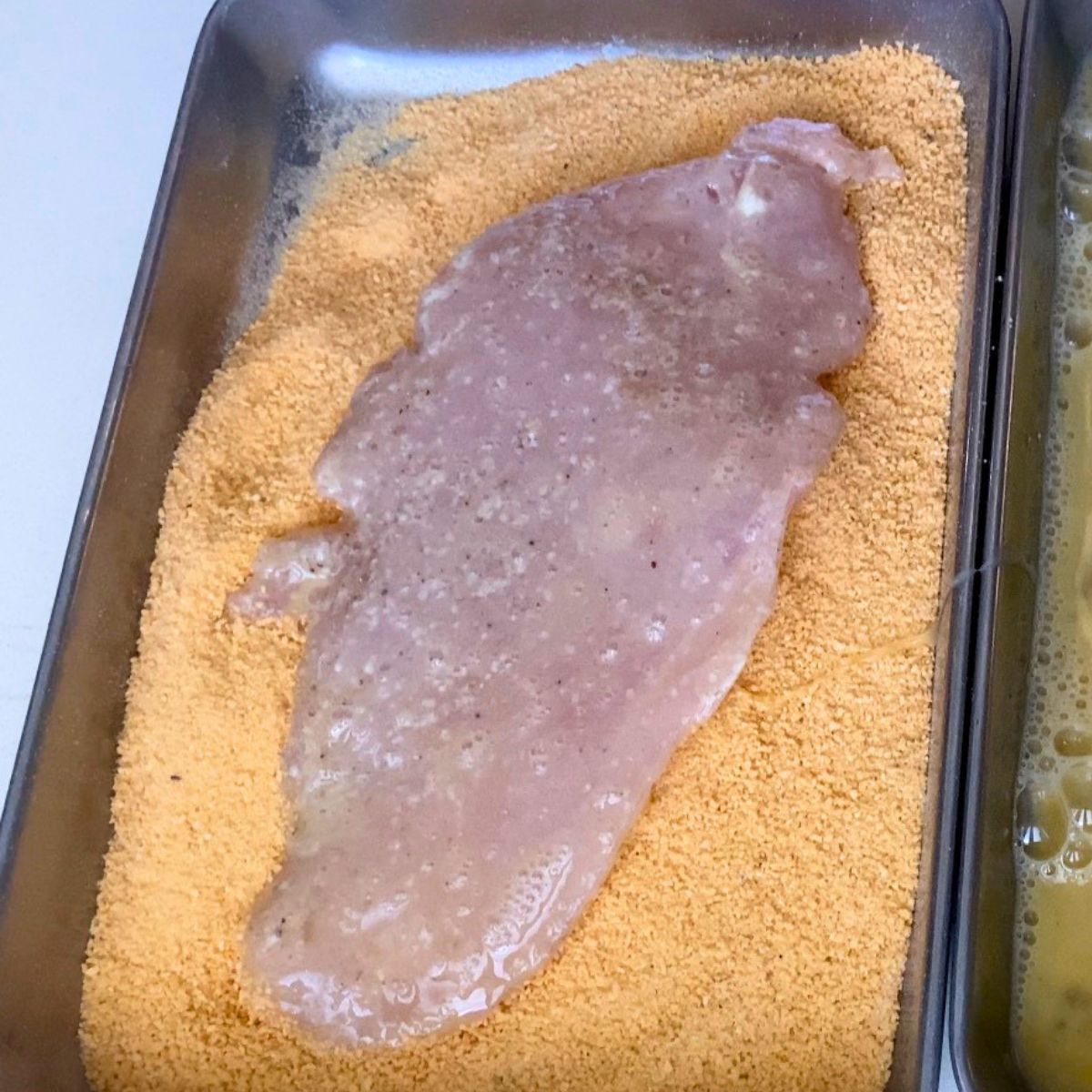 Coating the chicken with breadcrumbs.