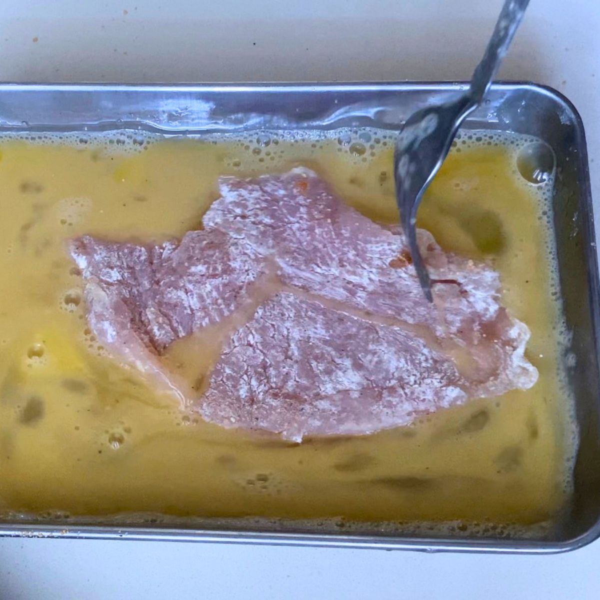 Coating chicken with beaten eggs.