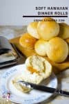 A stack of dinner rolls on a wooden board.