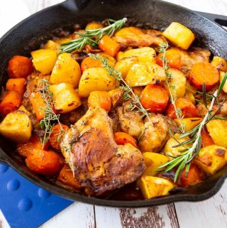 Roasted chicken, potatoes and vegetables in a skillet.