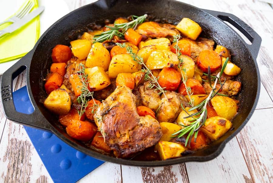 Roasted chicken, potatoes and vegetables in a skillet.