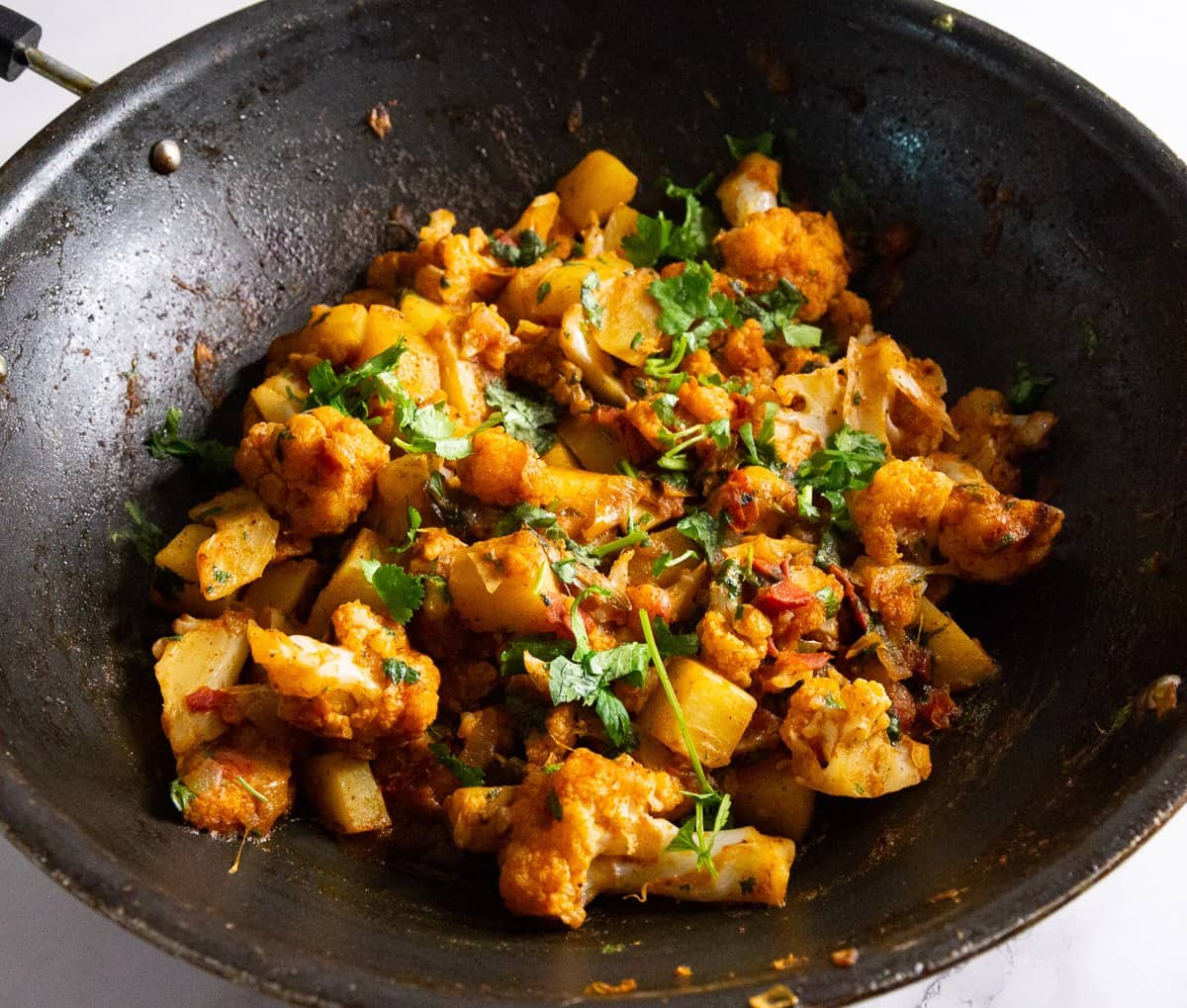 A skillet with aloo and gobi vegetable.