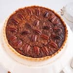 A tart with pecans cooling a cake stand.