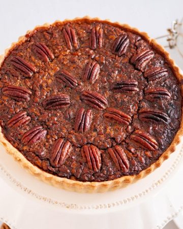 A tart with pecans cooling a cake stand.