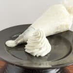 A whipped cream swirl on a black plate