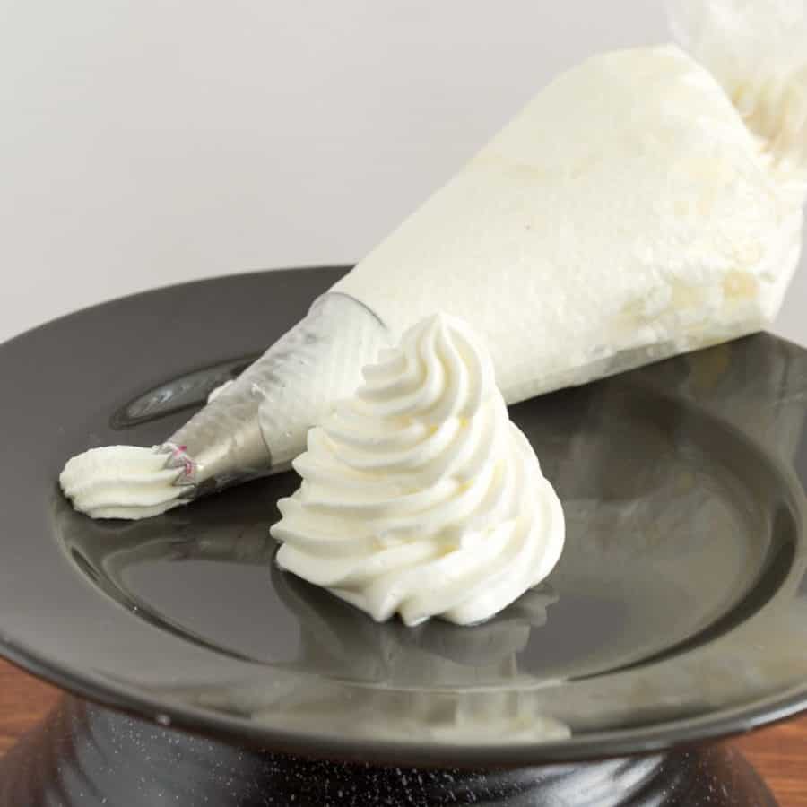 A whipped cream swirl on a black plate